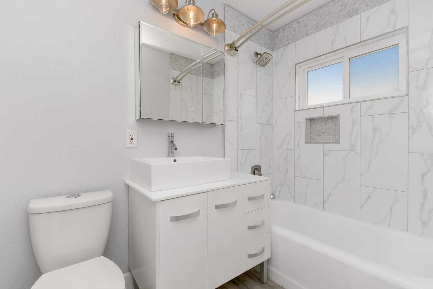 White marble tile for shower, in wall shower shelf, stainless steal rods and faucets, modern shower sink, hidden medicine cabinet, rustic bathroom lights, hexagon backsplash, grey wood floors, modern bathroom design, Remodeling Source of San Diego; Bathroom remodeling San Diego, near me; plumbing near me