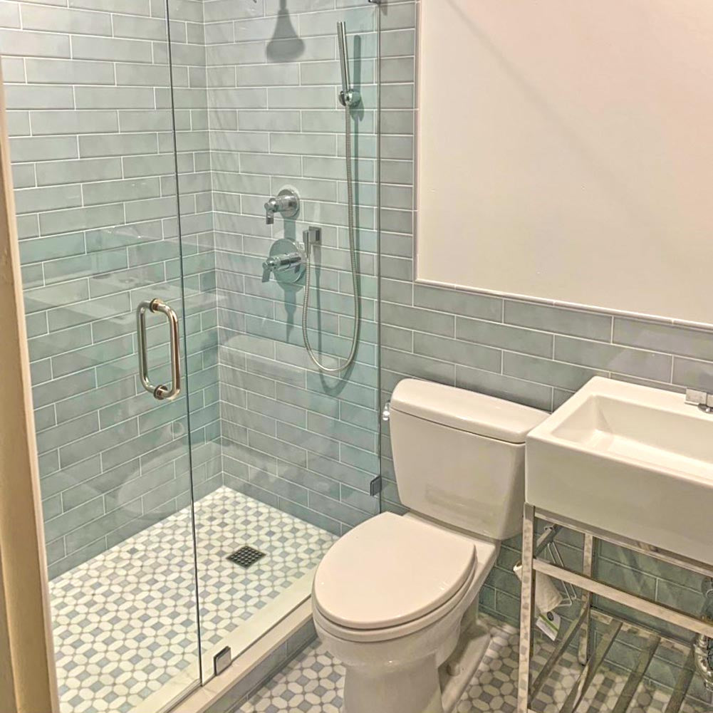 Contemporary bathroom design with unique grey and white tile flooring, sleek minimalist sink, and modern rain-style shower – San Diego Remodeling and Kitchen Remodel showcase. Remodeling Source of San Diego