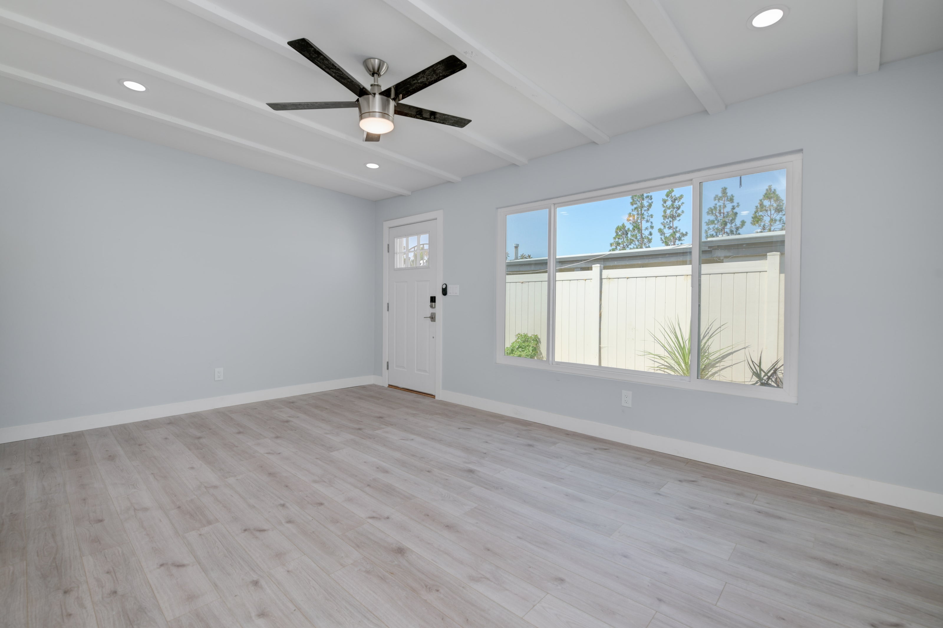 Grey Wood Floors, large front windows, living room remodel, classic white doors, off white walls, modern lighting fixtures. Remodeling Source of San Diego, Modern living room remodel San DIego