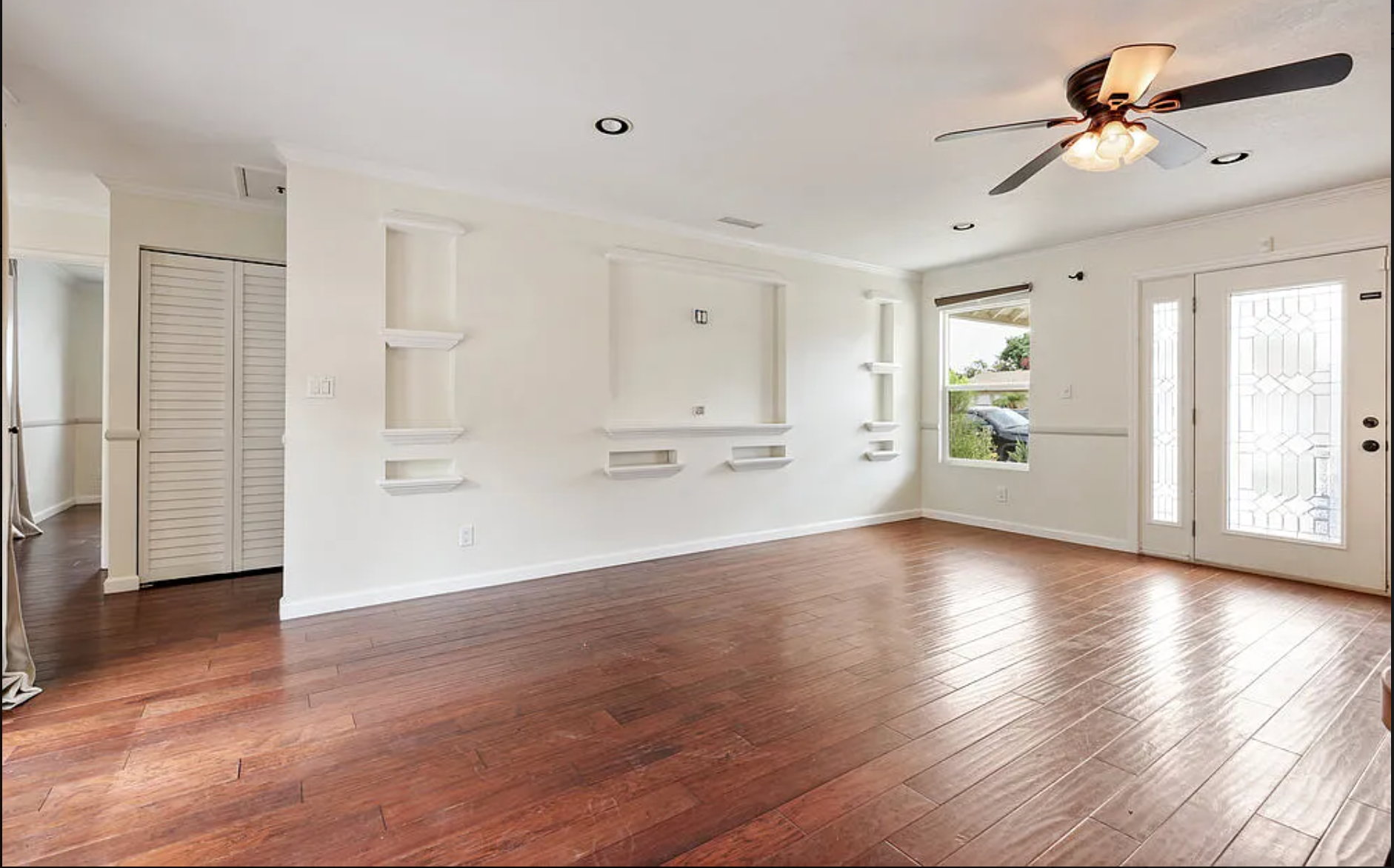 Red wood floors, modern Elegant glass door, large living room windows, built-in Shelving in living room, modern lighting fixtures. Modern living room remodel. Remodeling Source of San Diego; Living room remodel san diego